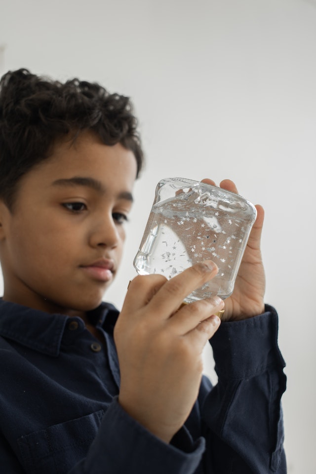 boy watching sparkling material moving slowly in a container